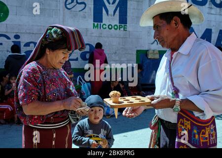Lady dressed in the colorful typical costume of the Ixil community buying an ice cream for her son. Stock Photo