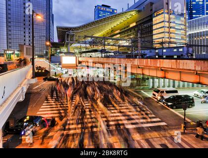 Crowded street crossing in Osaka city near OSaka umeda railway train station at sunset. Stock Photo
