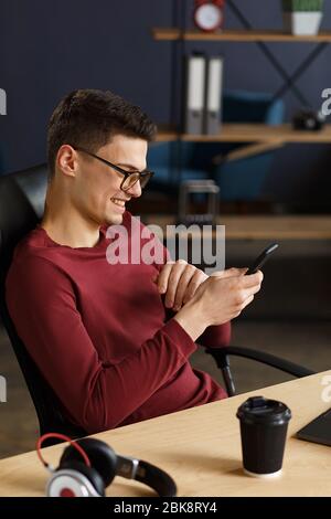Young man using smartphone and smiling. Happy businessman using Stock Photo