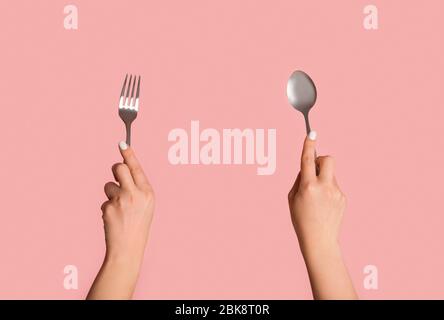Closeup of unrecognizable girl holding spoon and fork on pink background Stock Photo