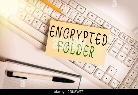 Handwriting text writing Encrypted Folder. Conceptual photo protect confidential data from attackers with access White keyboard with note paper and cl Stock Photo
