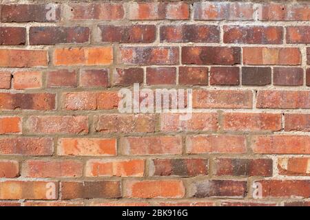 Rustic antique clay brick wall texture background with peppered bricks in shades of red and brown Stock Photo