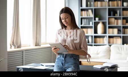 Beautiful young woman using computer tablet, standing at home Stock Photo