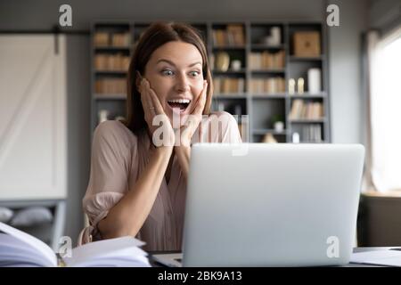 Excited surprised woman looking at laptop screen, reading news Stock Photo