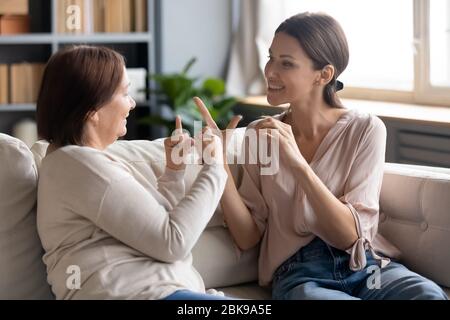 Happy adult daughter and older mother speaking sign language Stock Photo
