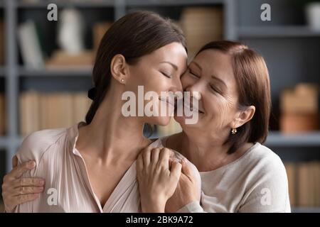 Happy adult daughter and mature mother hugging, expressing love Stock Photo