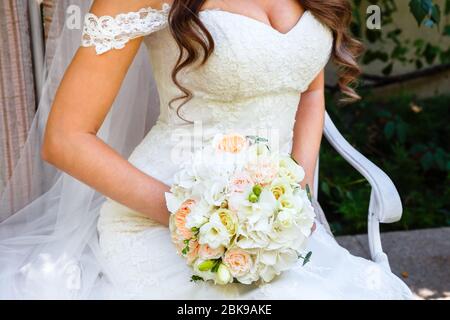 Sitting Bride holding a beautiful wedding bouquet of roses and eustoma. Stock Photo
