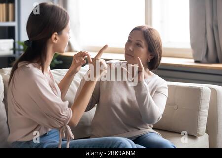 Middle aged mother and adult daughter speaking sign language Stock Photo
