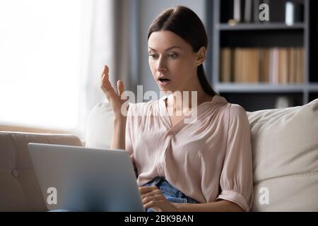 Shocked young woman looking at laptop screen, unexpected news Stock Photo