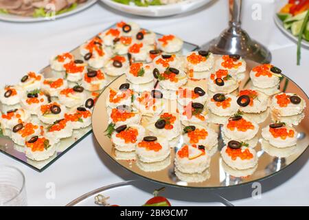 Appetizers with red caviar on a mirror plate on a festive table in restaurant Stock Photo