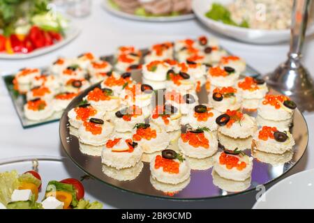 Appetizers with red caviar on a mirror plate on a festive table in restaurant Stock Photo