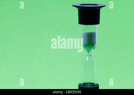 hourglass with white sand on green background Stock Photo