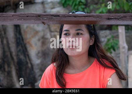 An Asian lady is thinking alone. Thai lady sitting alone outside. Stock Photo