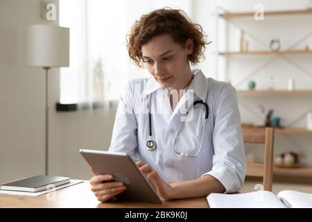 Serious professional doctor using digital tablet computer at work Stock Photo