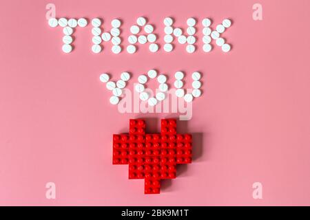 International's nurses day, week concept, Text Thank you by tablets and red heart on pink background.