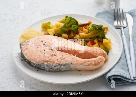Steam salmon and vegetables, healthy diet. White plate on concrete table, side view Stock Photo