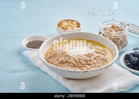 Oatmeal with butter and toppings. Blueberries, Chia seeds, almond flakes, banana. Side view Stock Photo
