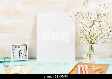 Mockup with blank white frame on blue table against wooden wall, alarm, flower in vaze Stock Photo