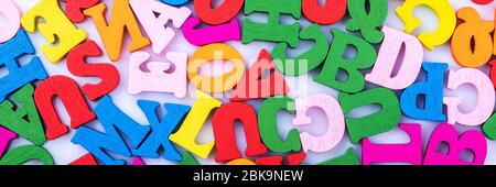 Letters of the alphabet are wooden scattered randomly macro photography isolated on a white background. Close up. Stock Photo