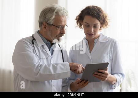 Medical team of two professional doctors talking using digital tablet Stock Photo