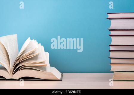 A large, thick hardcover book is lying on a light-wood table. The book is open, the pages are fanned out, and on the back is a blue background with sp Stock Photo