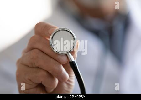 Old doctor hand holding medical stethoscope, close up view Stock Photo