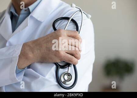 Senior male doctor holding stethoscope in hand, close up view Stock Photo