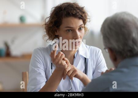 Female physician talking to senior patient at visit in hospital Stock Photo