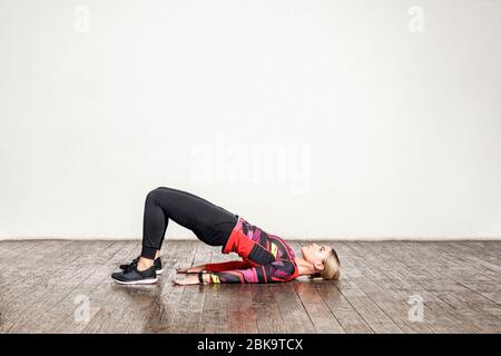 Athletic woman in tight sportswear practicing yoga, doing bridge pose bending back, stretching body, training flexibility, muscle strength. Health car Stock Photo