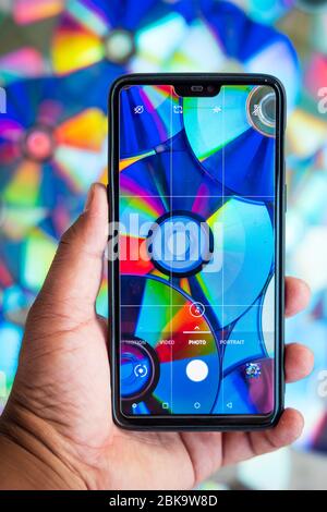 Holding phone with camera pointed against a pile of compact discs Stock Photo