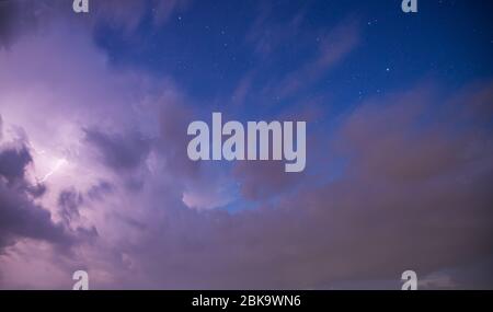 Dramatic storm clouds with blue sky, stars and lightening bolt Stock Photo