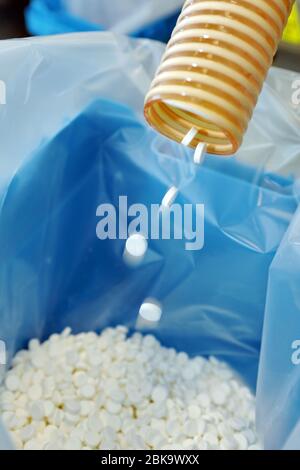 Production of tablets. Tablets poured into sterile packaging. Many pills. Manufacturing white, round tablets for health. Stock Photo