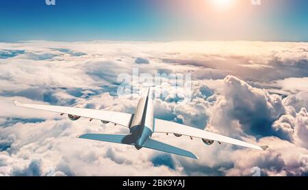 Rear view of airplane or airliner flying over sea of clouds and sun shining in the background. Travel, transportation or transport 3d rendering and mi Stock Photo