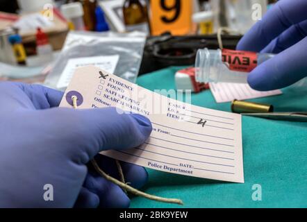 Police expert writes about label evidence number, Various laboratory tests forensic equipment, conceptual image Stock Photo