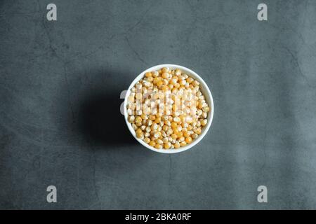Corn seeds in white porcelain bowl on concrete, stone background. Stock Photo