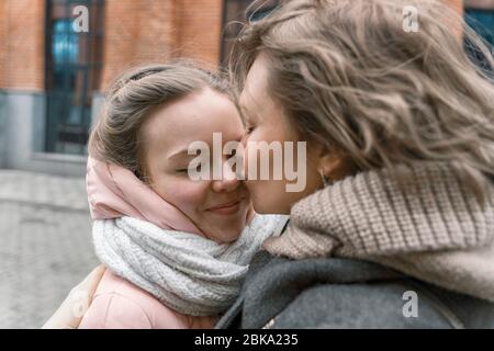 mature mother hugs and kisses her adult daughter on the forehead, girl smiling. family relationship concept Stock Photo