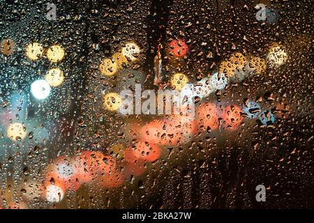 drops of rain on the glass, against the background of the night street Stock Photo