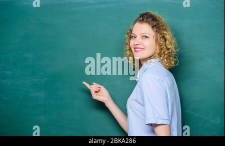 Passionate about knowledge. Teaching could be more fun. Teacher best friend of learners. Good teacher is master of simplification. Woman teacher in front of chalkboard. Teacher explain hard topic. Stock Photo