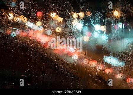 large raindrops on the glass, against the background of the night street Stock Photo