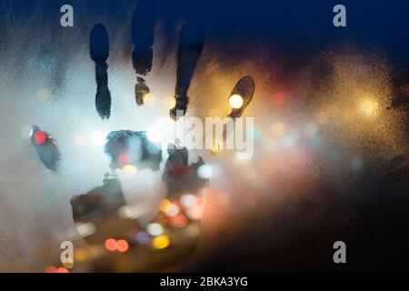 a handprint on a misted glass, against a background of a night street Stock Photo