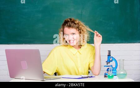 fascinating biology lesson. biology experiment. make notes about chemistry research results. happy student with microscope and beaker. girl in classroom laboratory with computer. Stock Photo