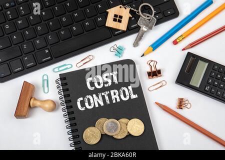 COST CONTROL. Black notebook and computer keyboard on a white office desk Stock Photo
