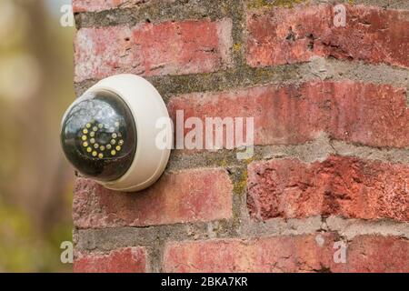 Fake security camera on the wall outside. security camera on a brick pillar in the yard. Stock Photo
