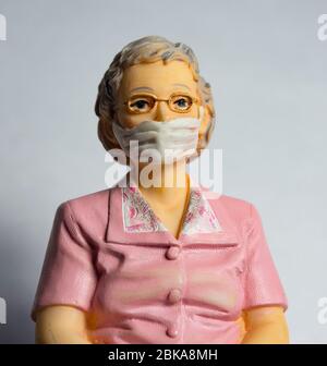 Female pensioner wearing a face mask,covid-19,corona virus protection,miniature figurines Stock Photo