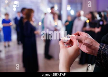 Burning candle in the hands of the newlyweds Stock Photo