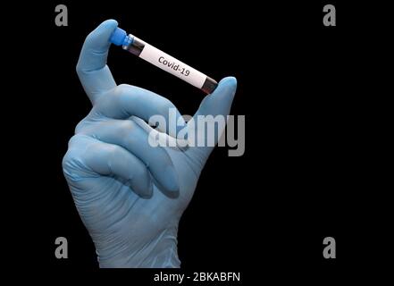 Hand in glove holding a test tube with the inscription covid-19 isolated on a black background. Sample with testing blood. Stock Photo