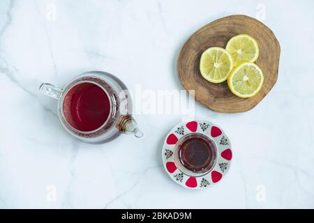 Brewed fresh tea and traditional Turkish tea glass with a sliced lemon in wooden platter on marble background. Traditional, healthy and organic Stock Photo