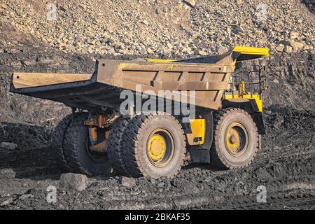 Big yellow mining truck laden anthracite moves open pit coal mine Stock Photo