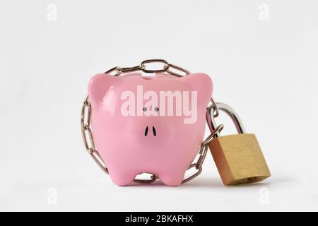 Piggy bank locked with chain and padlock on white background - Concept of savings and financial protection Stock Photo