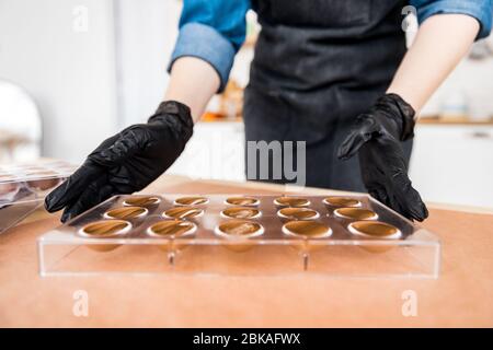 Chef or chocolatier Shakes chocolate molds for sweets Stock Photo